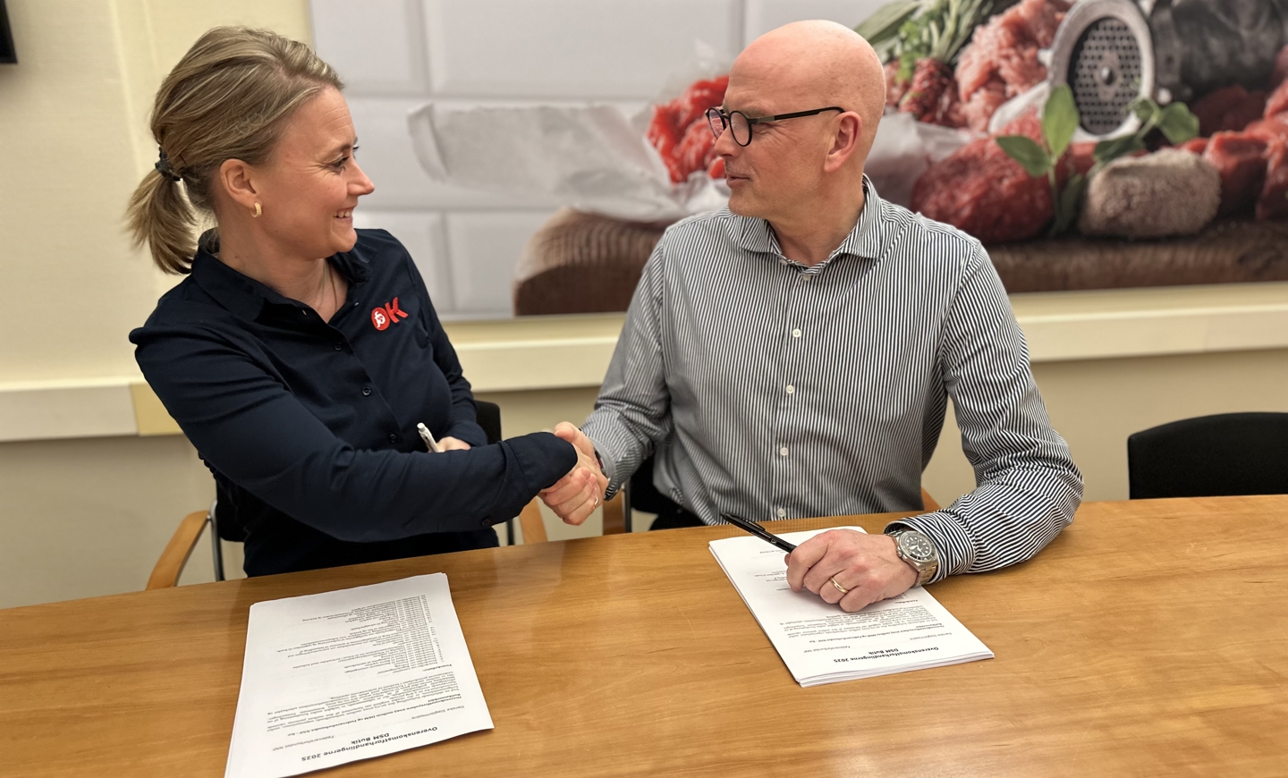 Forhandlingssekretær i Fødevareforbundet NNF Mette Bisgaard og direktør i DSM Leif Wilson giver hinanden hånden på en ny treårig overenskomst